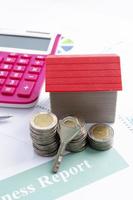 close-up da chave com pilha de moedas de dinheiro e casa vermelha para o conceito de empréstimo hipotecário foto
