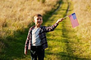 garotinho com bandeira dos eua ao ar livre. américa comemorando. foto