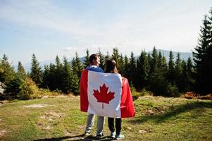 Feliz dia do Canadá. casal com grande celebração de bandeira canadense nas montanhas. foto