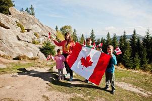 Feliz dia do Canadá. família de mãe com três filhos realiza grande celebração da bandeira canadense nas montanhas. foto