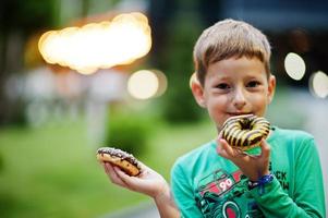 menino com donuts no quintal à noite. saborosa comida de donut gostoso. foto