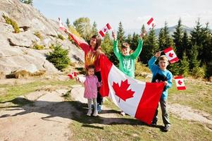 Feliz dia do Canadá. família de mãe com três filhos realiza grande celebração da bandeira canadense nas montanhas. foto