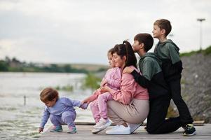 Amor de mãe. mãe com quatro filhos ao ar livre no cais. esportes família numerosa passa tempo livre ao ar livre. foto