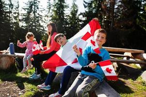 Feliz dia do Canadá. família de mãe com três filhos realiza grande celebração da bandeira canadense nas montanhas. foto