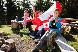 Feliz dia do Canadá. família de mãe com três filhos realiza grande celebração da bandeira canadense nas montanhas. foto