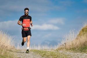 um corredor de atleta com barba treina em uma estrada de montanha foto