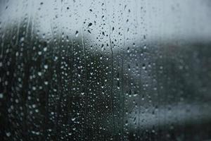 gotas de chuva embaçadas na superfície dos vidros da janela com fundo nublado. conceito de fundo dramático foto