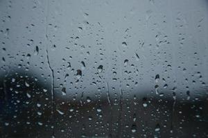 gotas de chuva na superfície de vidros de janela com fundo nublado. conceito de fundo dramático foto