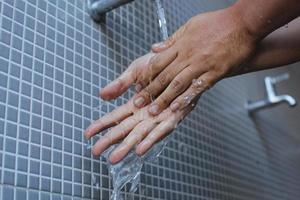 um homem muçulmano faz a ablução, conhecida como wudu, como um ritual de purificação para rezar. lavar a mão para evitar contrair o vírus corona foto