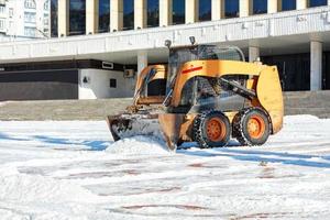 a niveladora ágil limpa a área da neve em um dia claro de inverno. foto