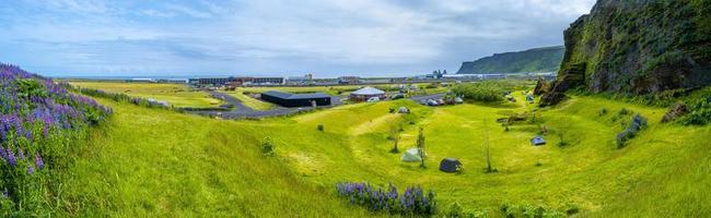 vista panorâmica sobre um parque de campismo na cidade de vik, perto dos pilares de rocha de reynisdrangar, sul da islândia no dia de verão. foto