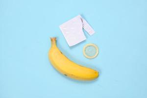 educação sexual com bananas e contracepção isolada em fundo azul foto