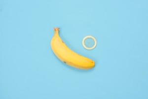 educação sexual com bananas e contracepção isolada em fundo azul foto