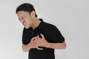 ataque cardíaco ou coração partido de jovem asiático com emoção ferida usar camisa preta foto