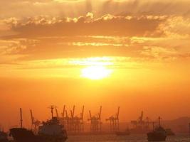 navio de carga e guindastes no porto do porto em tanjung perak surabaya com fundo do céu por do sol. foto