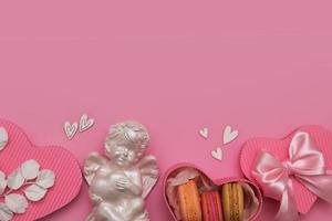 cama plana de dia dos namorados com caixa de presente, biscoito, arco, anjo, corações em um fundo rosa com espaço de cópia foto