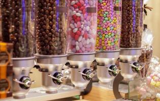 variedade colorida de doces de frutas em tubos de plástico em uma loja de doces. jujubas para venda na loja. bolas de goma de mascar coloridas em uma máquina de pastelaria. foco seletivo. foto
