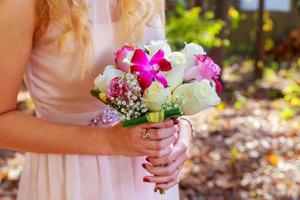 a noiva segurando o buquê de rosas cor de rosa e brancas foto