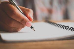 mão de homem com caneta escrevendo no caderno. foto