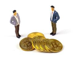 figura em miniatura de dois empresários em pé perto da moeda bitcoin. foto