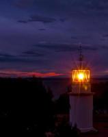 o farol brilhando na noite escura na costa da espanha foto