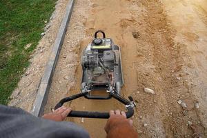 trabalhador bate no chão com uma máquina vibratória. vista do topo. foto