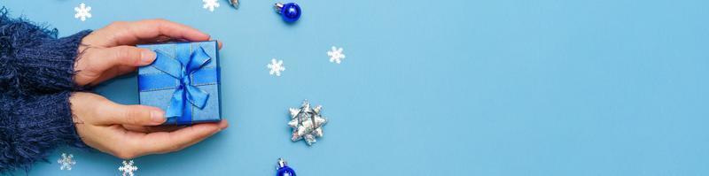 bolas e flocos de neve e presente de ano novo nas mãos da mulher de suéter escuro foto