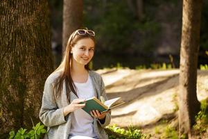 linda garota no parque com um livro na mão foto