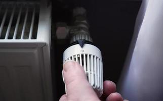 desligando o termostato no radiador para economizar energia devido ao aumento dos custos de aquecimento foto