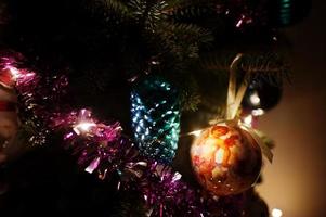 árvore de natal com guirlandas brilhantes na noite em casa. foto