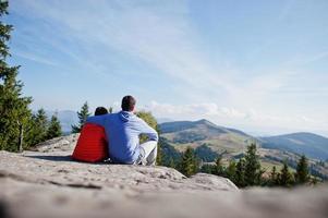 pai com filho. crianças caminhando em um lindo dia nas montanhas, descansando na rocha e admirando a vista incrível dos picos das montanhas. lazer de férias em família ativo com diversão kids.outdoor e atividade saudável. foto