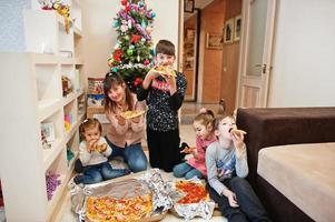 família feliz com quatro filhos comendo pizza em casa. foto