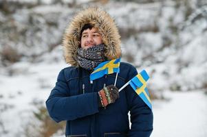 homem escandinavo com bandeira da suécia na paisagem sueca de inverno. foto