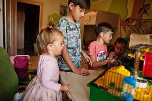 quatro crianças segurando seus animais de estimação favoritos nas mãos. crianças brincando com hamster, tartaruga e papagaios em casa. foto