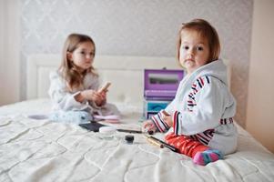 duas irmãs fazendo maquiagem na cama no quarto. foto