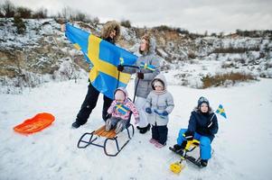 família escandinava com bandeira da suécia na paisagem sueca de inverno. foto