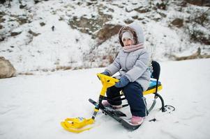 menina desfrutar de um passeio de trenó. trenó infantil. garoto andando de trenó no inverno. foto