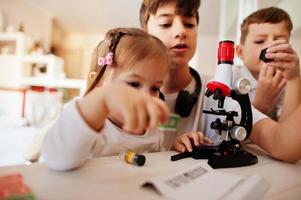 crianças usando microscópio aprendendo aula de ciências em casa. foto