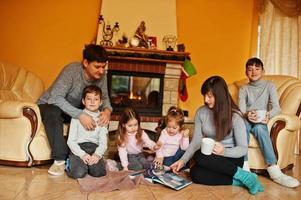 feliz jovem grande família em casa por uma lareira na sala de estar quente em dia de inverno. foto