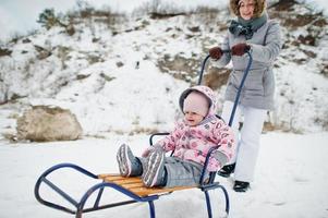 mãe e bebê desfrutam de um passeio de trenó. trenó infantil. garoto andando de trenó no inverno. foto