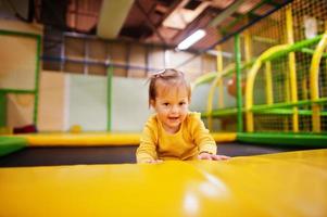 linda menina pulando em um trampolim no centro de recreação indoor. foto