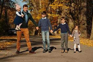 pai com quatro filhos no parque outono. foto