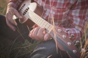 jovem toca ukulele ao ar livre foto