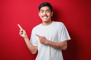 homem asiático sorrindo e apontando para apresentar algo do seu lado foto