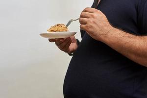 um homem gordo comendo comida não saudável