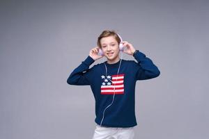 aplicativo de música. lindo garoto usando telefone com fones de ouvido, ouvindo uma ótima música foto