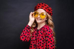 retrato menina de óculos amarelos em vestido vermelho com corações e boina vermelha foto