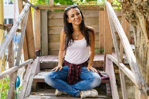 mulher feliz em roupas casuais está sentada nos degraus da varanda e sorrindo. foto