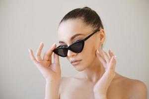 menina modelo de moda beleza com cabelo castanho usando óculos de sol elegantes toques foto