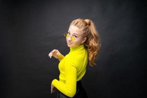 linda garota adolescente caucasiana em uma camiseta amarela e saia preta posando foto